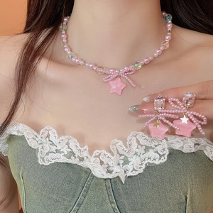 Detail view of sweet pink pearl bow necklace and matching star earrings on model