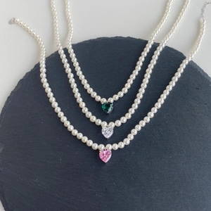 Detail of silver pearl necklaces with pink, green and white heart-shaped zircon pendants