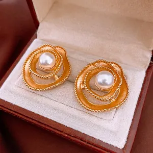 Vintage floral pearl earrings with gold spiral design and beaded edges in a jewelry box