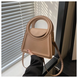 Detail of beige trapezoid handbag with circular handle and fine stitching detail