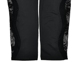Detailed close-up of floral lace patchwork on the hem of black skinny leggings