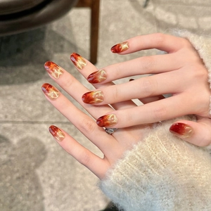 Handmade wine red cat-eye press-on nails with golden shimmer gradient in oval shape