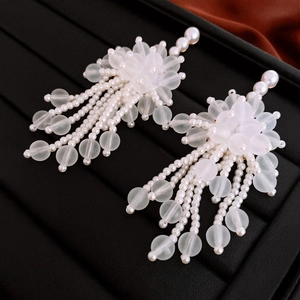 Eleganti orecchini a fiore in acrilico bianco con lunghe nappe di perle su vassoio