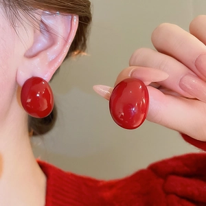 Macro shot of glossy red oval drop earrings with silver pins for a minimalist style
