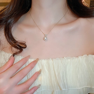 Elegant close-up of a minimalist single pearl necklace with zircon on a female model