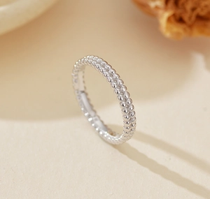 Macro shot of minimalist S925 sterling silver double-row bead ring on textured paper