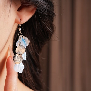 Détail de longues boucles d'oreilles avec disques dorés et pétales en acrylique bleu