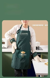 Detail of dark green silicone oven mitts and waterproof apron set in a kitchen