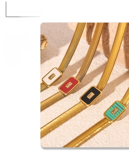 Detail of gold snake bone necklaces with colorful square stones in white red black and green
