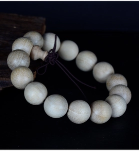 Macro shot of 20mm natural camphor wood beads with fine grain on a dark background