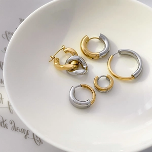 Detailed shot of two-tone gold and silver circular hoop earrings in a ceramic bowl