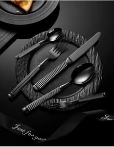 Detailed view of black stainless steel cutlery set with striped handles on a dark plate