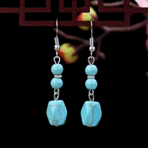 Detailed close-up of bohemian turquoise drop earrings with vintage floral silver accents