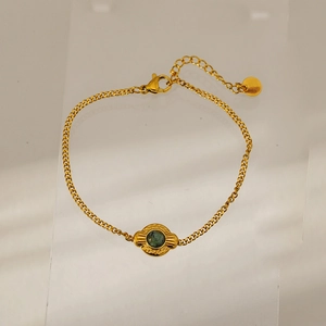Detail of gold-plated stainless steel bracelet with green stone and hammered pendant