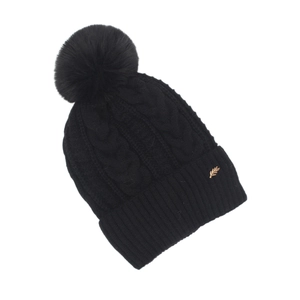 Détail du bonnet en tricot noir avec motif torsadé, pompon et breloque feuille dorée