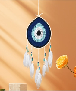 Detail of bohemian evil eye dreamcatcher with white feathers and wooden beads on wall