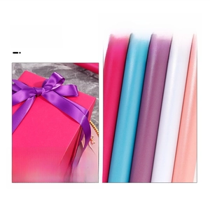 Detail von Geschenkpapier mit matter Textur und lila Satinband auf einer Geschenkbox