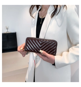 Détail d'un long portefeuille en cuir verni foncé avec surpiqûres en V et fermeture éclair