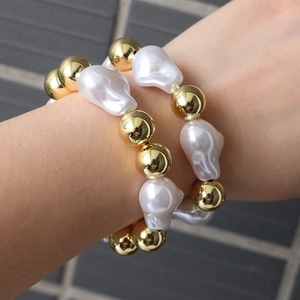 Macro detail of golden beads and baroque pearls on a double-layer adjustable bracelet