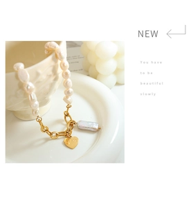 Macro shot of Baroque freshwater pearl necklace with gold heart pendant and LOVE engraving