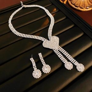 Detailed view of silver heart pendant necklace and matching drop earrings on black display