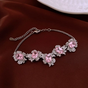 Close-up of silver bracelet with pink square zircon stones on brown silk fabric