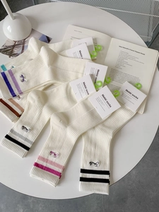 Detail of white mid-calf sports socks with colorful stripes and Smile embroidery