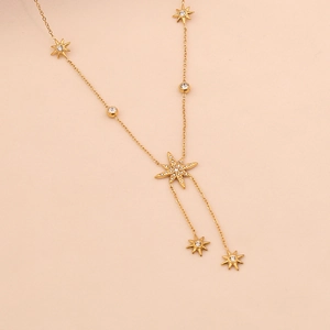 Detail of gold Y-shaped necklace featuring a crystal-encrusted eight-pointed star pendant