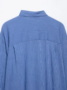 Gros plan de l'empiècement d'une chemise à rayures bleues montrant les finitions du tissu