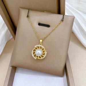 Detailed macro view of a gold necklace with a pearl pendant and cubic zirconia accents