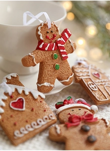 Detailed close-up of resin gingerbread man and house ornaments with hanging cords