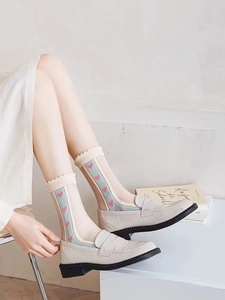 Close-up of sheer light green socks with pink heart embroidery and wavy lace cuffs