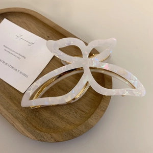 Macro detail of a pearlescent white butterfly claw clip on a wooden tray decor