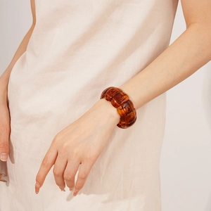 Detail of a chunky amber resin geometric bracelet on wrist with soft lighting