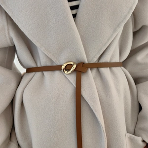Caramel brown leather waist belt with gold geometric buckle on a beige wool coat
