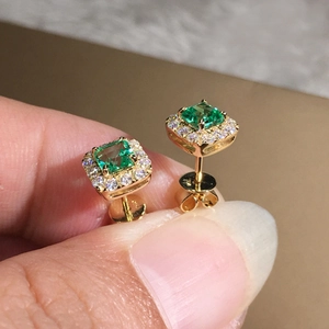 Macro shot of square emerald zircon earrings with halo stones in gold-plated setting