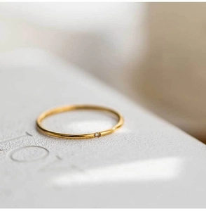 Detailed macro view of a slim gold titanium ring with a tiny inset sparkling zircon stone