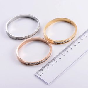 Detailed size measurement of 18k gold and silver crystal bangles with a ruler