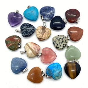 Natural crystal heart pendants in amethyst and tiger eye with silver bails on white backdrop