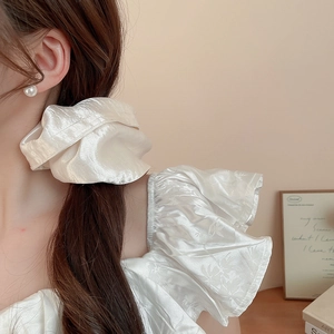 Close-up of oversized cream satin scrunchie with soft silk texture and elegant shine