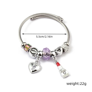 Detail view of steel bangle with purple crystal bead, heart lock, and lipstick charm