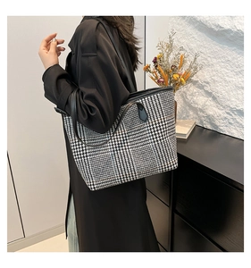 Detail of large houndstooth tote bag with leather straps on a stylish model