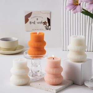 Artistic geometric ribbed pillar candles in orange, white and pink for home decor