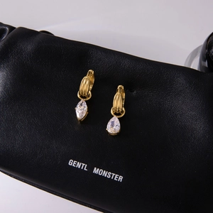 Macro shot of gold teardrop earrings with sparkling cubic zirconia on black jewelry box
