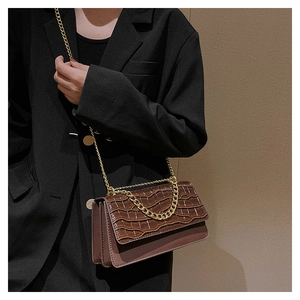 Détail d'un sac à main marron texture crocodile avec une chaîne dorée élégante