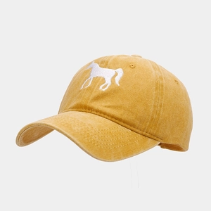 Close-up of a horse embroidery on a mustard yellow washed cotton baseball cap