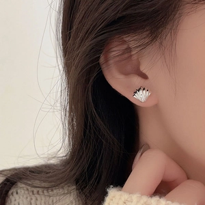 Detail of silver shell-shaped stud earring worn by model for an elegant daily look
