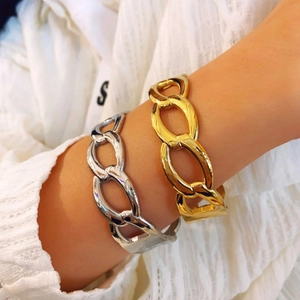 Minimalist chunky chain bracelet in gold and silver finish worn on wrist over white knitwear