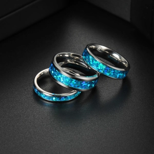 Three minimalist titanium steel rings with blue opal inlay on black background