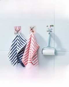 Detail of four strong adhesive wall hooks with nature patterns on white tile wall